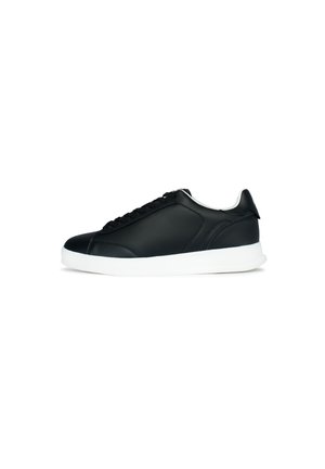 Zapatilla de cuero negro con un acabado suave, punta redonda y cordones delanteros. Presenta una suela de goma blanca y un interior blanco en contraste.