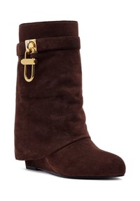 Brown suede ankle boot with a curved design, featuring a gold buckle accent and a rounded toe. Textured surface and low wedge heel.