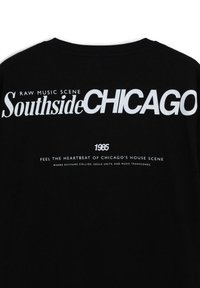 T-shirt in cotone nero con una grafica audace in bianco che recita "SouthsideCHICAGO" e ulteriore testo sulla scena musicale di Chicago.