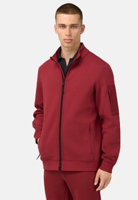 Roter Reißverschluss-Sweatshirt aus weichem Stoff, mit hohem Kragen, Seiten Taschen und einer Klappen Tasche am linken Ärmel.