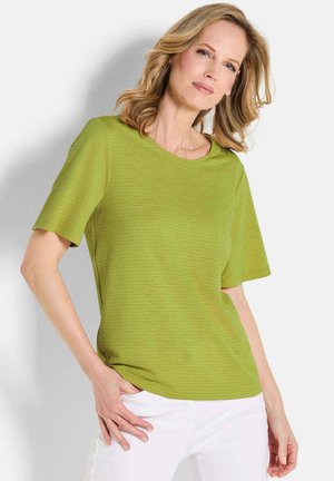 Haut vert texturé à manches courtes avec un col rond, associé à un pantalon blanc. Le tissu présente un motif subtil et une finition lisse.