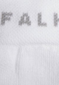 Calzino bianco con trama a maglia, caratterizzato da testo grigio. La vista ravvicinata mette in evidenza i dettagli fini e la qualità del materiale.