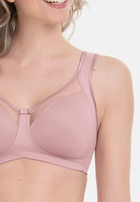 Zacht roze beha met gevormde cups, gaasaccenten en verstelbare bandjes. Beschikt over een centrale haaksluiting en een gladde textuur.