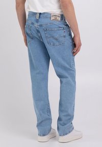 Jeans in denim azzurro chiaro con una vestibilità relax, dotati di un'etichetta con il marchio sulla vita, tasche posteriori e orli risvoltati.