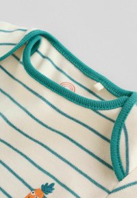 Raida jumpsuit vaalean- ja turkoosinvärisessä raidassa, jossa on pehmeä tekstuuri, pyöreä kaula-aukko ja brodeerattu porkkanasuunnittelu alhaalla.