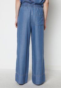 Ljusblå denimbyxor med vida ben och elastisk midja, som har en enda bakficka och en avslutad fåll vid fållen.