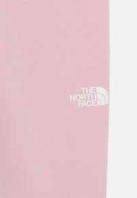 Felpa di cotone rosa chiaro con logo bianco "The North Face" in basso a destra, che mostra una consistenza liscia.