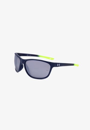 Occhiali da sole neri opachi con lenti scure, punte delle aste traslucide verde neon e logo Under Armour bianco sull'asta.