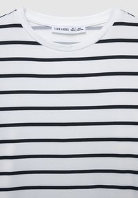 T-shirt a righe bianche e nere con scollatura rotonda. Il tessuto appare liscio e morbido, con strisce orizzontali di spessore variabile.
