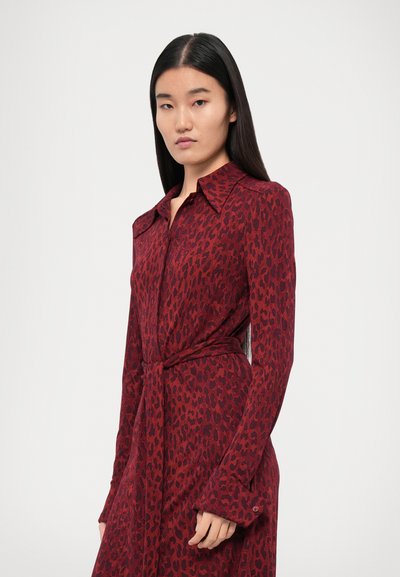Rochie cu imprimeu leopard roșu, cu mâneci lungi și talie căptușită. Prezintă un guler ascuțit și manșete cu nasturi. Textură de țesătură netedă și moale.