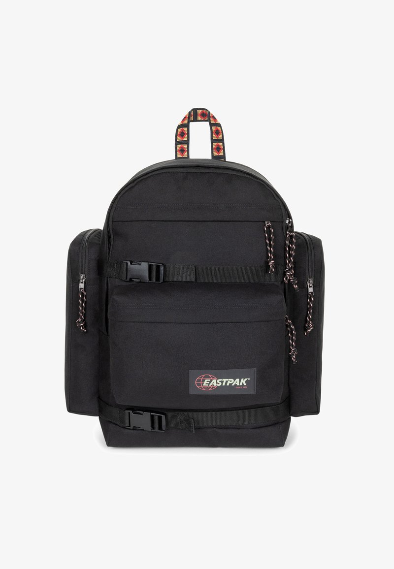 Le sac à dos en tissu noir présente une conception ergonomique arrondie, des compartiments à double zip et des accents rayés tissés sur la poignée.