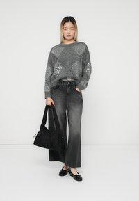 Pulover gri tricotat cu paiete, asortat cu blugi negri cu talie largă. Accesoriile includ o geantă din material textil neagră și pantofi plate negri.