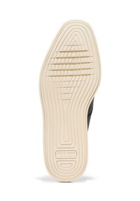 Černá podrážka boty s texturovaným béžovým gumovým povrchem. Obsahuje soustředné drážky a značkovou etiketu s nápisem "COLE HAAN GRAND.360" blízko paty.