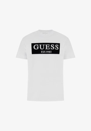 T-shirt bianco in cotone con una grafica rettangolare nera con la scritta "GUESS" e "EST. 1981" in bianco. Maniche corte, scollatura a girocollo.