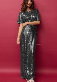 Abito nero con paillettes, maniche corte, design fino al pavimento, con un motivo testurizzato e una leggera lucentezza, abbinato a calzature casual.