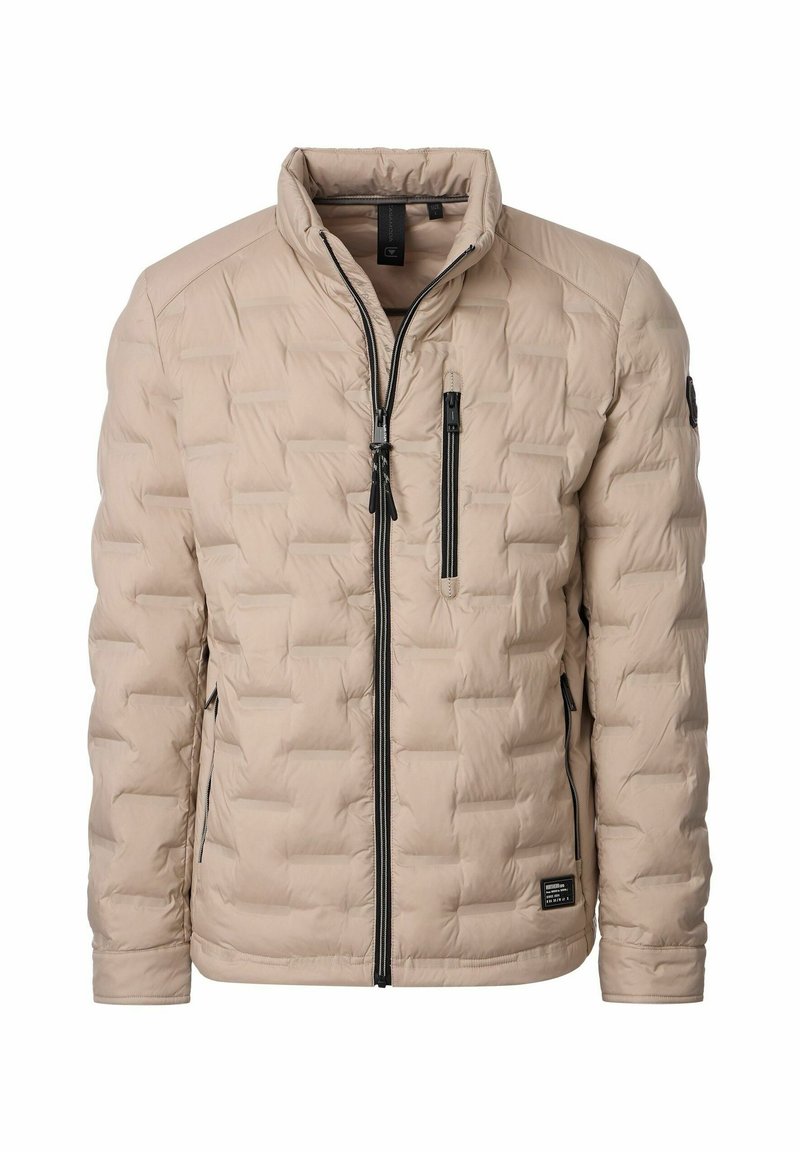 Beige polstret jakke med quiltet design, høj krave og sorte lynlåse. Har to sidelommer og en lomme på brystet. Lavet af letvægtsmateriale.