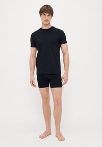 T-shirt nero a maniche corte e boxer abbinati, realizzati in tessuto morbido, caratterizzati da un taglio classico e un design minimale senza motivi né loghi.