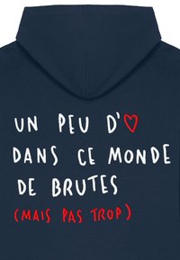 Temno modra kapucar z belim in rdečim vezenim besedilom v francoščini, vključno z motivom srca na prvi vrstici.