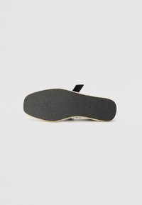 Zwarte rubberen zool met een gestructureerde grip, voorzien van een lichtbruine rand. Gladde oppervlakte met een lichte kromming, ontworpen voor stabiliteit en comfort.