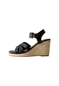 Black leather wedge sandals with crisscross straps, adjustable ankle buckle, and woven jute platform sole, featuring a smooth finish.