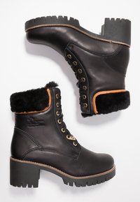 Stivaletti neri in pelle con colletto in pelliccia sintetica, chiusura con lacci frontale, occhielli dorati e tacco spesso con righe. Accenti in pelle marrone.