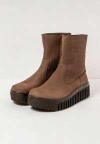 Bottines brunes en cuir souple avec une finition texturée, dotées d'une semelle en caoutchouc épaisse et striée pour plus de hauteur et d'adhérence.