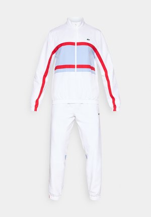 Chándal blanco con chaqueta con cremallera que presenta franjas horizontales rojas y azules, puños elásticos y pantalones a juego con acentos de logo.