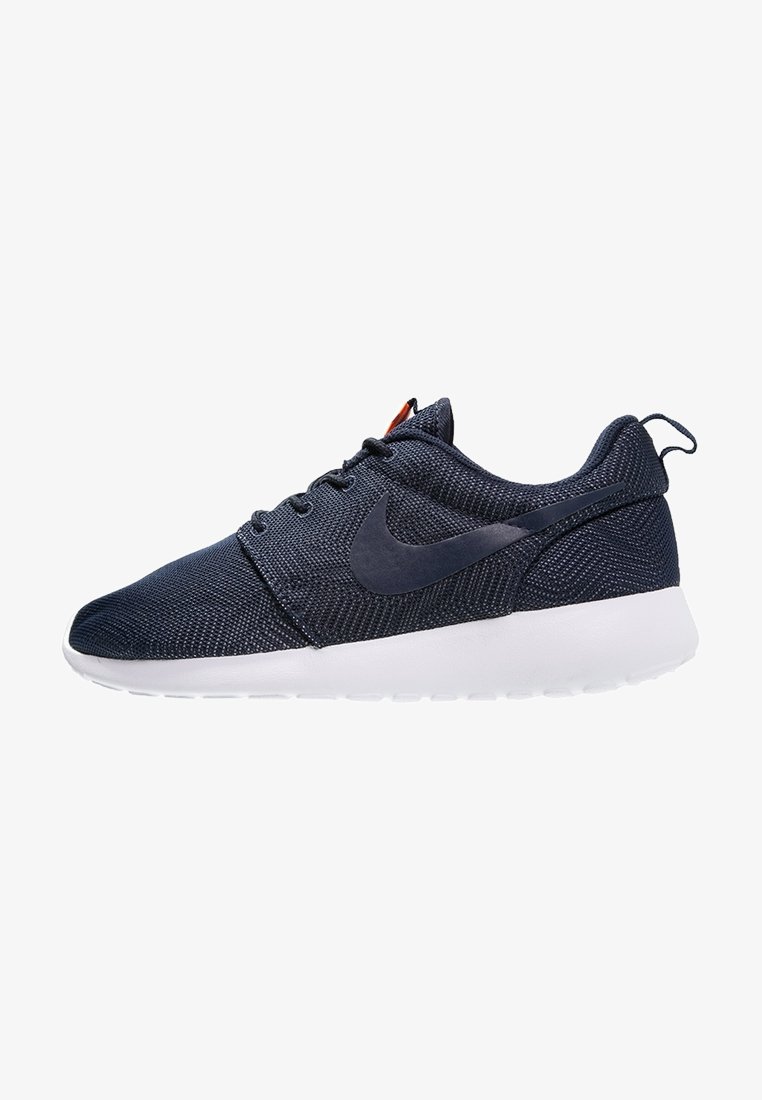 Baskets en mesh bleu marine avec une surface texturée, une semelle en caoutchouc blanche et un logo bleu foncé en accent. Présentent un design épuré et une fermeture à lacets.