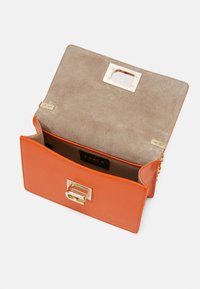 Oranžová kožená kabelka Furla typu clutch s zlatým zapínáním, béžovým semišovým podšívkou a otevřeným klapkovým víkem, které odhaluje hlavní oddíl.