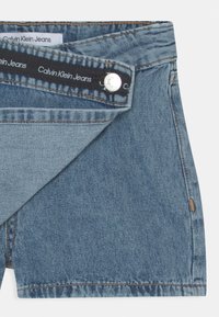 Jeansshorts i ljusblått med knappstängning, med en sömnad nederkant och en märkesetikett på midjebandet. Ren design utan ytterligare detaljer.