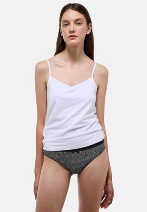 Débardeur blanc en coton à fines bretelles, assorti à une culotte noire ornée d'un motif à pois blancs. Texture lisse, design décontracté.