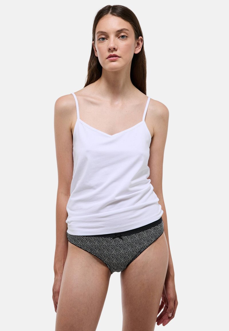 Débardeur blanc en coton à fines bretelles, assorti à une culotte noire ornée d'un motif à pois blancs. Texture lisse, design décontracté.