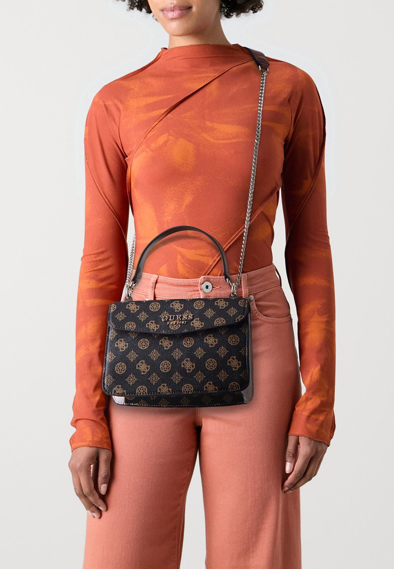 Borsa a tracolla nera con un design strutturato, manici doppi e tracolla a catena. Realizzata in materiale testurizzato con un emblema dorato, abbinata a una maglietta arancione.