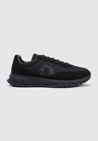 Zapatillas deportivas negras con parte superior texturizada, con un talón suave y una suela de goma negra con patrón. Logo en negro mate en el costado.