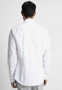 Witte lange mouwen shirt met een klassieke kraag, een soepele textuur en knoopmanchetten, voorzien van een ronde zoom en een subtiele merkimprint.
