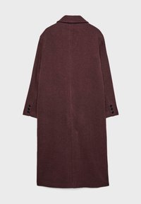 Lang, bordeauxfarvet uldfrakke med krave, lige snit og lange ærmer. Har sorte knapper ved manchetterne. Glat, struktureret stof.