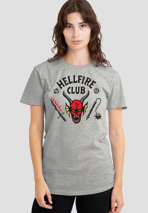 Gray cotton t-shirt featuring a bold graphic of a red devil skull with horns, swords, and "HELLFIRE CLUB" text in black. Short sleeves.