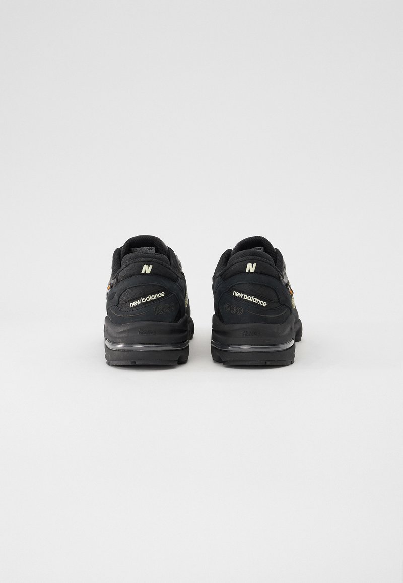 Scarpe da ginnastica nere con una parte superiore strutturata, dotate di un collo imbottito, dettagli riflettenti e una suola ammortizzata. Logo ben visibile.
