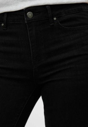 Svarta denimjeans med smal passform, med knappstängning, stickade fickor och subtil textur. Inga framträdande mönster eller dekorationer.