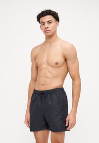 Shorts de bain noirs avec une taille élastique et un cordon de serrage. Comprend le logo "Calvin Klein" sur le côté gauche en broderie assortie.