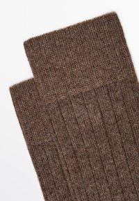 Brune ribbede strikkede sokker med et tekstureret design, der har et blødt, varmt materiale og en foldet kant øverst.
