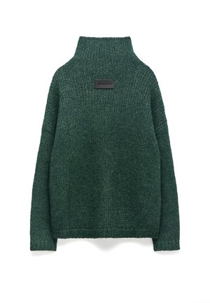 Dunkelgrüner Strickpullover mit hohem Kragen, lockerer Passform, überschnittenen Schultern und einem rechteckigen Patch auf der Rückseite mit geprägtem Text.
