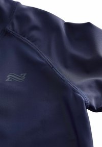 Marinblå träningströja med ett mjukt, stretchigt tyg. Har platta sömmar och en liten logotypdetalj på bröstet i en subtil ton.