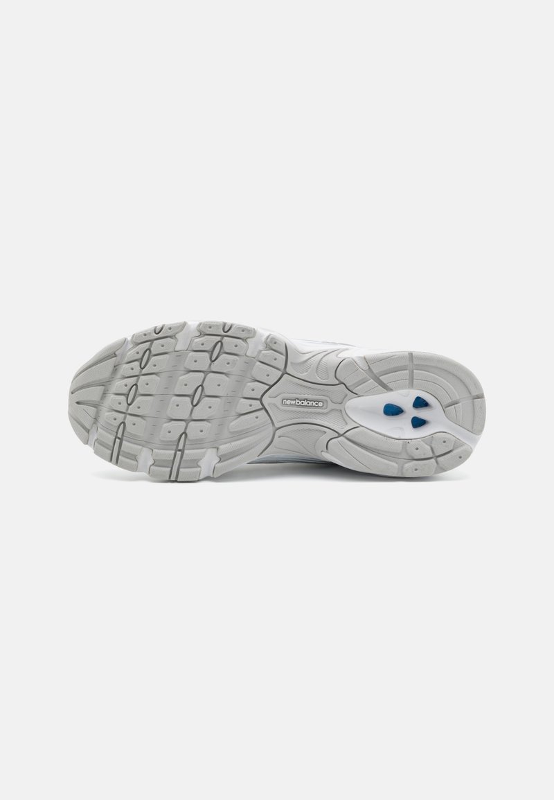 Semelle de chaussure de sport blanche avec un motif de grip, présentant des accents bleus et le logo New Balance. Fabriquée en caoutchouc, conçue pour l'adhérence et la durabilité.