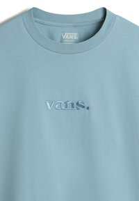 Light blue loose-fit t-shirt made of soft fabric, featuring an embroidered logo "vans." in darker blue positioned on the chest.