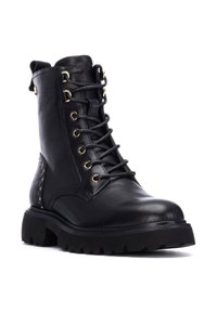 Bota de tobillo de cuero negro con ojales dorados, cordones y acentos metálicos. Suela negra resistente con un patrón de tracción texturizado.