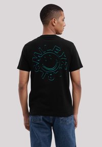 Schwarzes Baumwoll-T-Shirt mit einem großen, mehrfarbigen Smiley-Gesicht-Design auf der Rückseite. Kurze Ärmel und klassischer Schnitt.