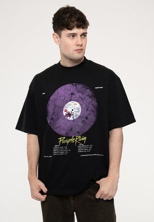 Black oversized t-shirt featuring a purple vinyl record graphic, white label at the center, and yellow text listing song titles and details.