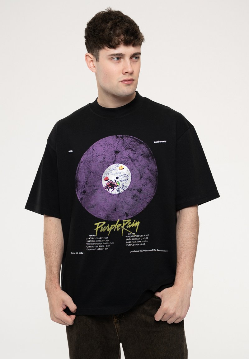 Black oversized t-shirt featuring a purple vinyl record graphic, white label at the center, and yellow text listing song titles and details.