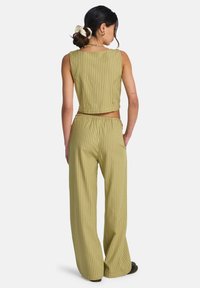 Ensemble deux pièces vert olive, avec des rayures verticales. Le crop top a un large décolleté, et le pantalon à jambes larges est doté d'une taille élastique.